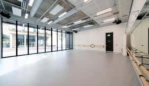 Interior de un estudio de danza con amplios ventanales y espejos