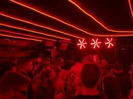Interior de la discoteca con público y ambiente de luces de neón rojas
