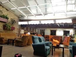 Interior del café con zona de sofás y techo acristalado que aporta luz natural