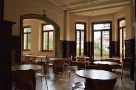 Interior del centro social con salón de techos altos y mesas para reuniones