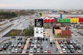 Vista general de las instalaciones del outlet con zona de aparcamiento y edificios de fachadas coloridas