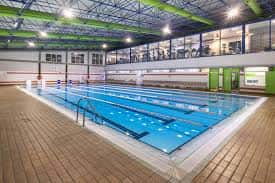Piscina interior climatizada con calles de natación y vista a la zona de gimnasio superior