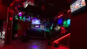 Interior del local con zona de escenario y escaleras bajo luces rojas