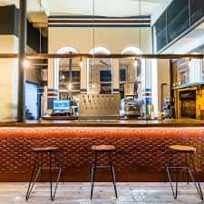Detalle de la barra interior con taburetes altos y grifos de cerveza en un ambiente moderno