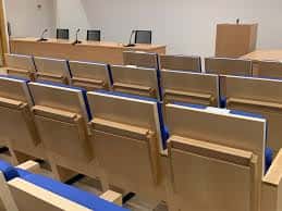 Interior del salón de actos con mesa de conferencias y filas de asientos azules