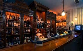 Barra de bar de estilo clásico con estanterías de madera tallada y gran variedad de licores