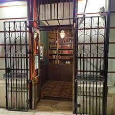 Entrada al local con verja de hierro y vista a una estantería de libros al fondo