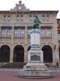 Monumento a San Francisco de Asís frente a la fachada de las Escuelas Municipales