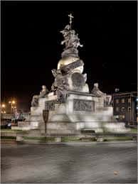 Vista nocturna iluminada del monumento central en la Plaza de Colón
