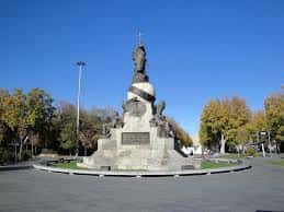 Perspectiva amplia de la Plaza de Colón con vegetación otoñal y el monumento de fondo