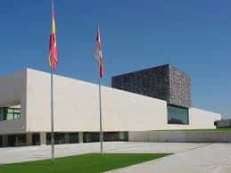 Vista exterior de la sede de las Cortes de Castilla y León con las banderas oficiales y cielo despejado