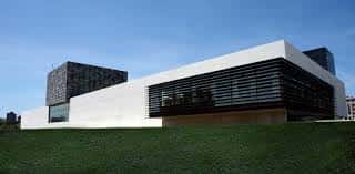 Perspectiva lateral del edificio destacando su arquitectura moderna y el diseño de lamas horizontales