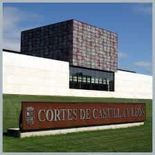 Detalle del rótulo institucional en la entrada de las Cortes de Castilla y León sobre zona ajardinada