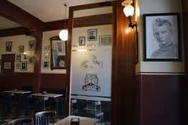 Zona de mesas con decoración de retratos en las paredes y ambiente bohemio