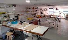 Área de taller equipada con mesas de trabajo y estanterías para proyectos creativos