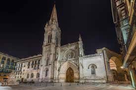 Fachada nocturna de la Catedral de Santiago iluminada, destacando su silueta arquitectónica en el entorno urbano