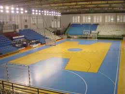Vista general del interior del pabellón deportivo con gradas azules y cancha de baloncesto