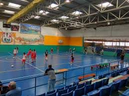 Actividad deportiva en el pabellón con jugadores en cancha y espectadores en gradas