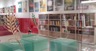 Exposición de arte en el Espacio Seminci con esculturas doradas y estanterías de libros al fondo