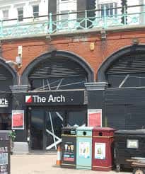 Fachada exterior de The Arch Nightclub en Brighton con arcos de ladrillo y letrero negro
