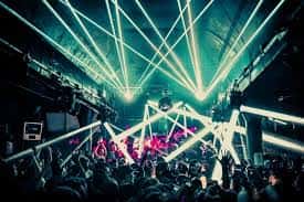Escenario del club con efectos de luz láser verde y público en primer plano