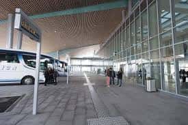 Interior de la estación con pasarela peatonal, autobús estacionado y viajeros en movimiento