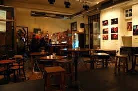 Interior de Sala El Cachorro con mesas, sillas y escenario en ambiente nocturno