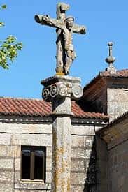 Cruceiro de piedra con figura de Cristo crucificado en la plaza de San Andrés de Comesaña