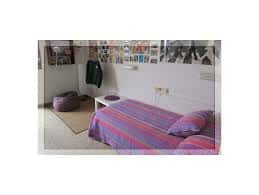 Habitación individual del colegio mayor con cama, escritorio y decoración estudiantil