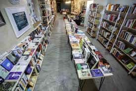 Vista general del interior de la librería con mesas de libros y estanterías a ambos lados
