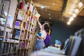 Cliente seleccionando libros en una estantería alta dentro de la librería