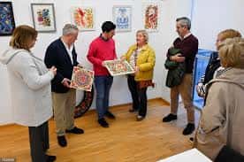 Exposición de arte en el centro cívico con visitantes observando obras