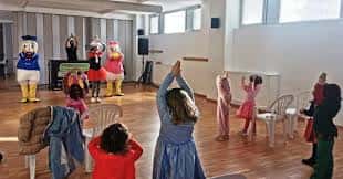 Evento infantil en el centro cívico con personajes disfrazados y niños participando