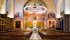 Interior del altar de la Iglesia de San Antonio con pinturas murales y bancos de madera