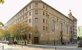 Vista lateral de la Iglesia de San Antonio en Pamplona con árboles y peatones en la acera