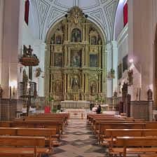 Nave central de la iglesia con bancos y retablo principal