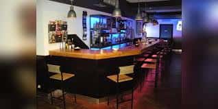 Interior del bar Sunset con barra de madera y taburetes