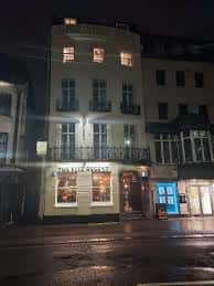 Vista nocturna del exterior del Fitz Regent con iluminación cálida y ambiente urbano