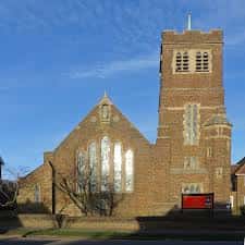 Vista exterior de la Iglesia del Buen Pastor en Brighton con su torre y fachada de ladrillo bajo un cielo azul