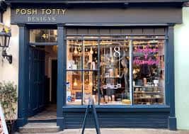 Vista exterior de la tienda Posh Totty Designs con letrero y escaparate iluminado