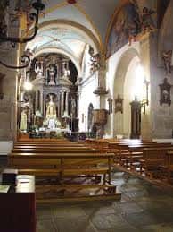 Interior de la iglesia con bancos de madera, altar y pinturas murales