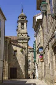 Vista exterior de la Iglesia de San Miguel dos Agros con su torre campanario bajo el sol