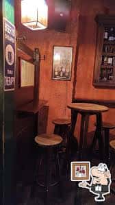 Detalle del interior del bar con mesas altas, taburetes y decoración rústica