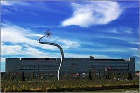 Vista exterior de la sede de Euskaltzaindia en Vitoria con escultura moderna y cielo azul
