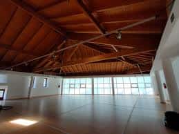 Gran sala interior con techo de vigas de madera y grandes ventanales, ideal para eventos