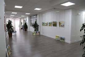 Interior del Centro Municipal de Santutxu mostrando un espacio amplio con suelo de madera y paredes blancas decoradas con cuadros