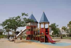 Área de juegos infantiles con estructuras de madera y toboganes en el Parque de la Alegría