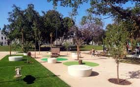 Área de descanso con bancos circulares y zonas verdes en el parque