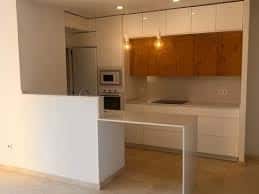 Cocina moderna con isla central y armarios blancos y madera