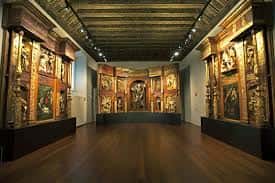 Interior de la sala de retablos con obras de arte religioso y techumbre de madera